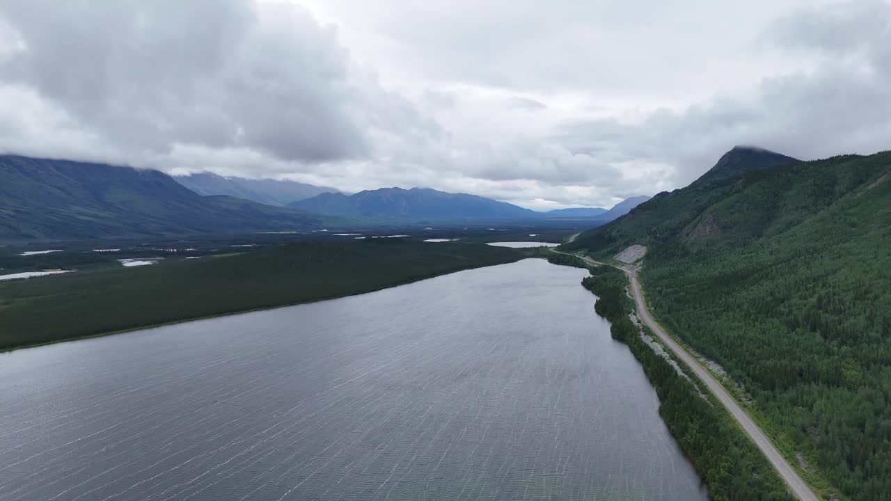 Majestic mountain lake wilderness with winding road and dramatic cloudy skies creating a serene landscape and inspiring adventure travel in Alaska