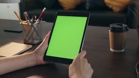 mujer sosteniendo una tableta digital con pantalla verde y dispositivo táctil navegando por internet.