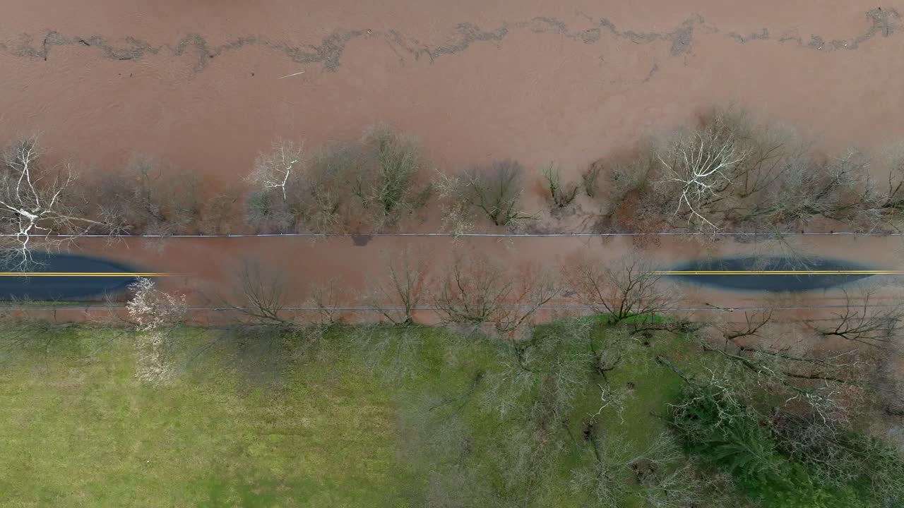 Aerial top down shot of muddy flooded street in suburb area with dirty river water after heavy rain in USA