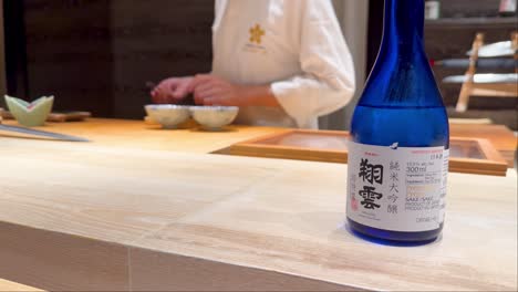 chef preparing food with sake bottle visible