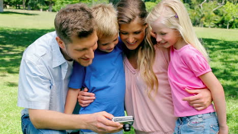familia mirando la galería de fotos de una cámara antes de mirar hacia la cámara