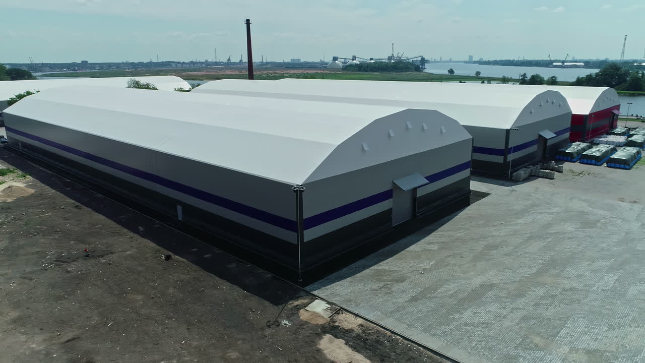 drone aéreo moviéndose hacia atrás disparado sobre una instalación de almacenamiento industrial que consta de grandes cobertizos en un día soleado