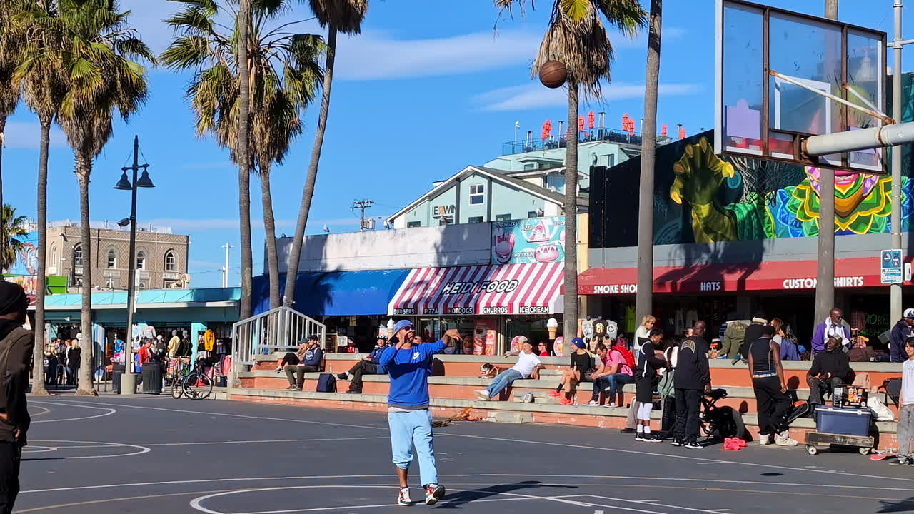 Outdoor basketball court at Venice beach with player shooting a basketball towards a hoop