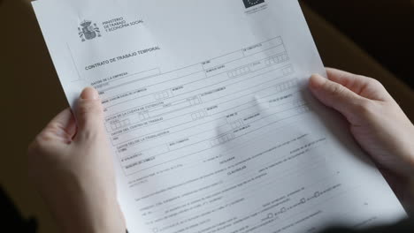mujer leyendo documento de trabajo temporal en español, arruinándolo y tirándolo, enojada y molesta