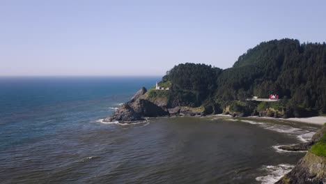 dolly in flight over cape cove shores on the pacific ocean, oregon coast approaches the famous heceta head 19th century lighthouse. scenic aerial