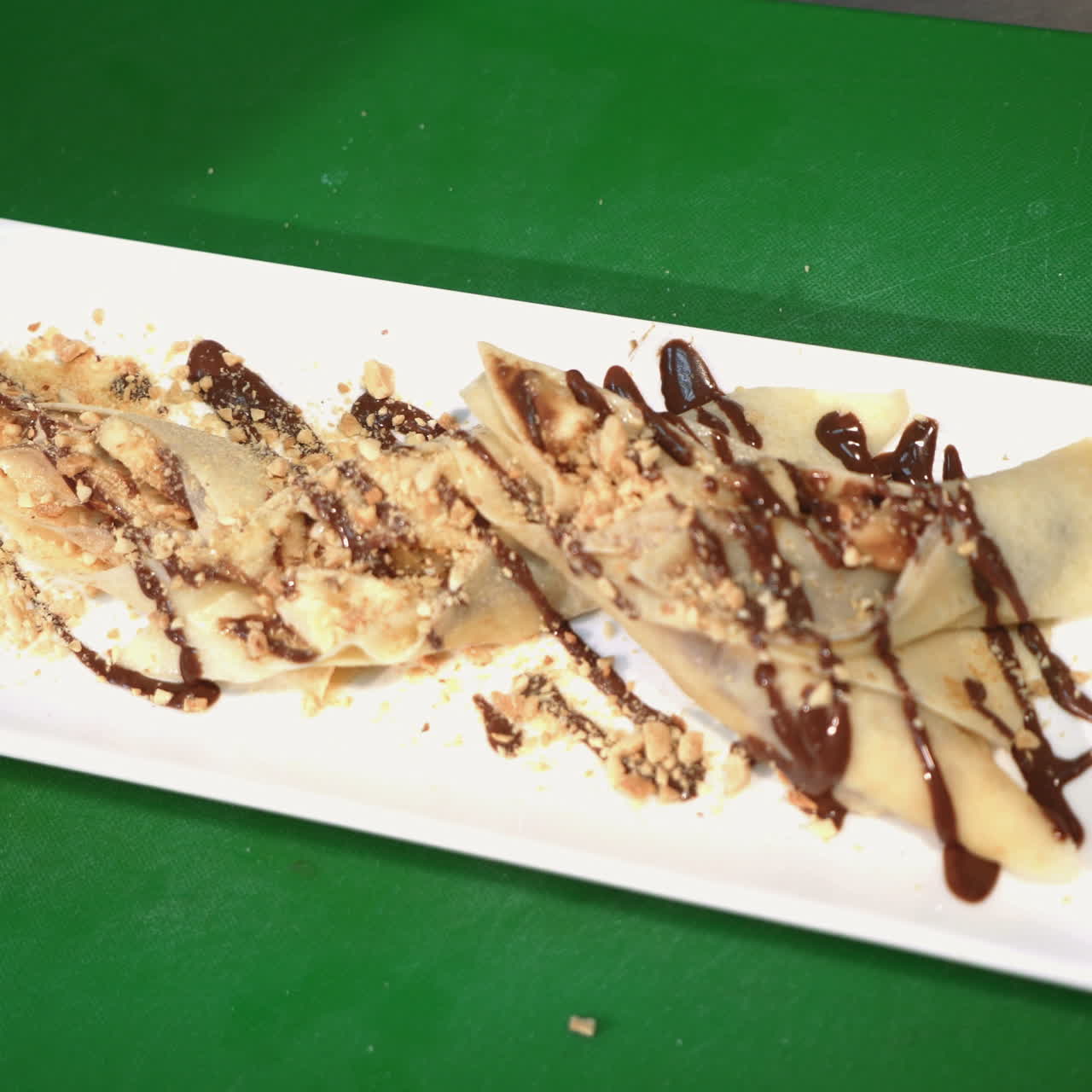 Chef is working on the presentation of the dish in a commercial kitchen. Pancakes with chocolate sauce on a plate Sqare video