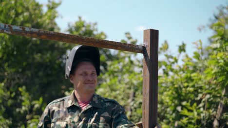 smiling-man-stands-and-looks-at-fence-carcass-against-garden