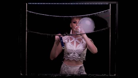 young girl does tricks with soap bubbles. she blows a pipe with bubbles of smoke, in turn