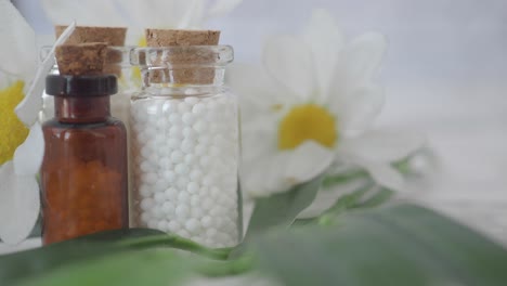 homeopathic globules in glass bottles with flowers and leaves