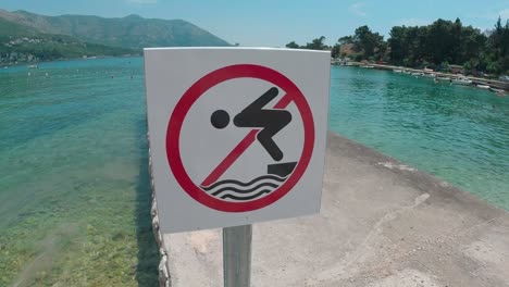 no diving warning sign on concrete pontoon by turquoise water lagoon landscape, vacation concept