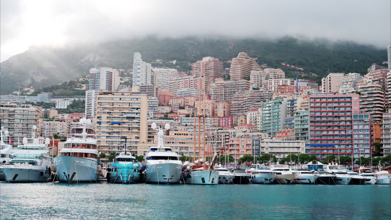 View of boats docked in the Monaco Marina with the skyline of the city on the background