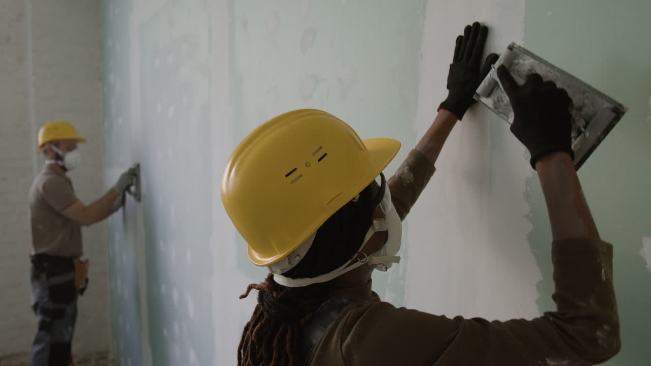 Construction workers applying drywall