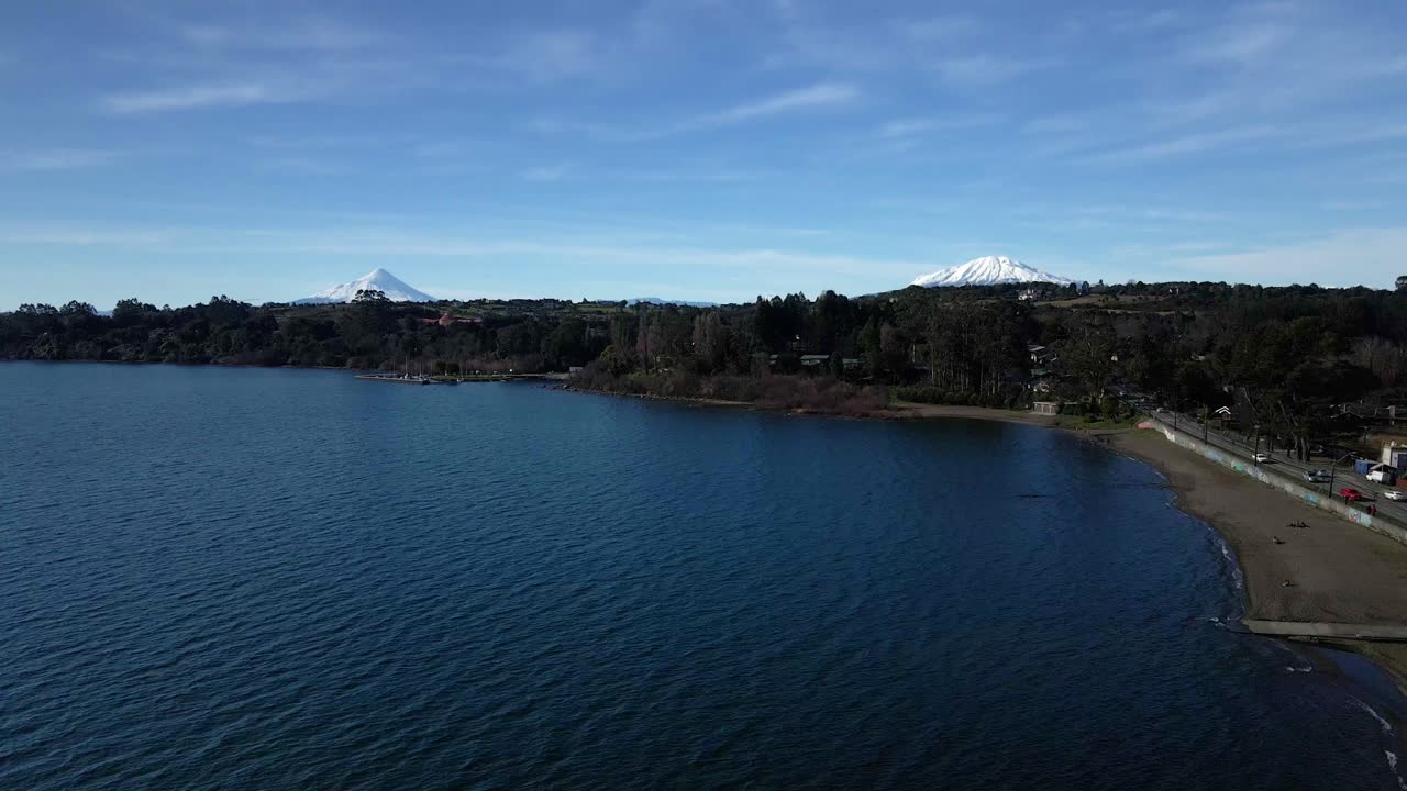 vista aérea dolly out playa hermosa de puerto varas, lago llanquihue, volcanes calbuco y osorno al fondo, sur de chile