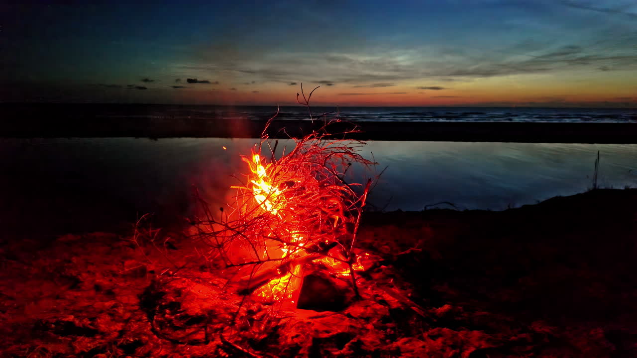 fuego de campamento quemando lentamente con pequeñas llamas, fuego junto al mar, acampando relajante por la noche