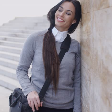 Grinning-woman-in-sweater-near-wall-looking-over