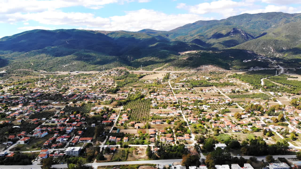 Asprovalta with multiple buildings and greenery, green hills on the background. Aegean sea coast. Sunny day. Greece