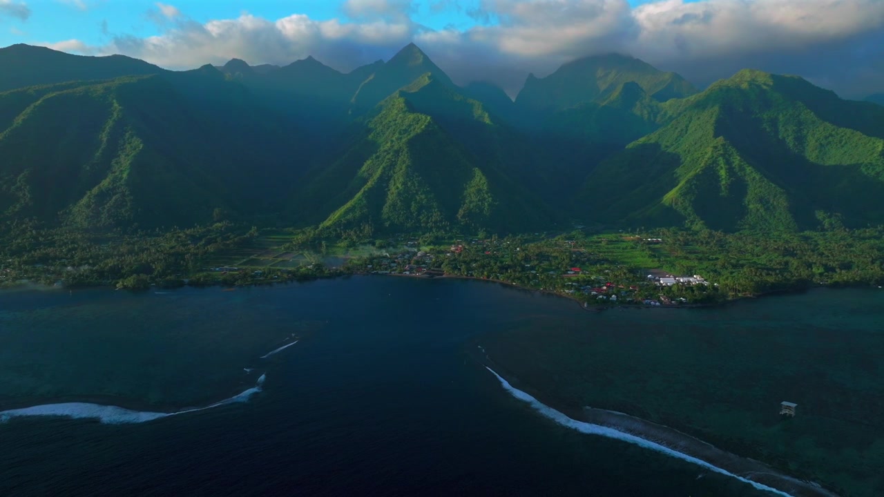 Tahiti lagoon landscape aerial drone harbor view French Polynesia Teahupo'o surf wave Passe Havea coral reef South Pacific Ocean island golden sun rays volcano peaks low clouds coastline back pan up