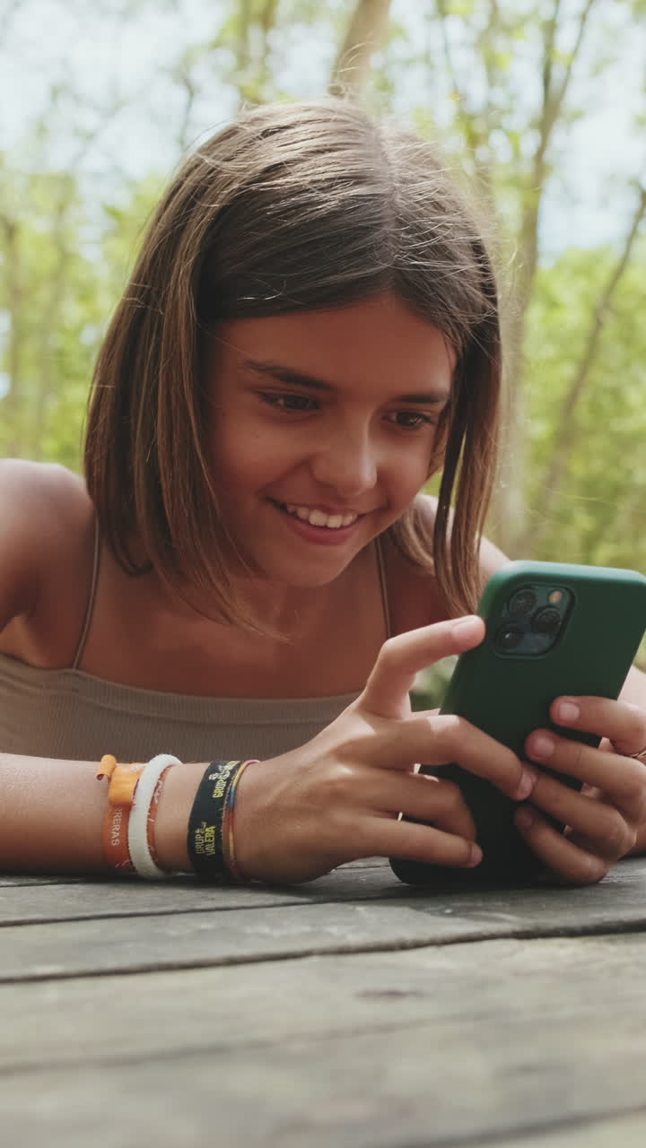 Giovane ragazza felice che sorride mentre usa lo smartphone all'aperto