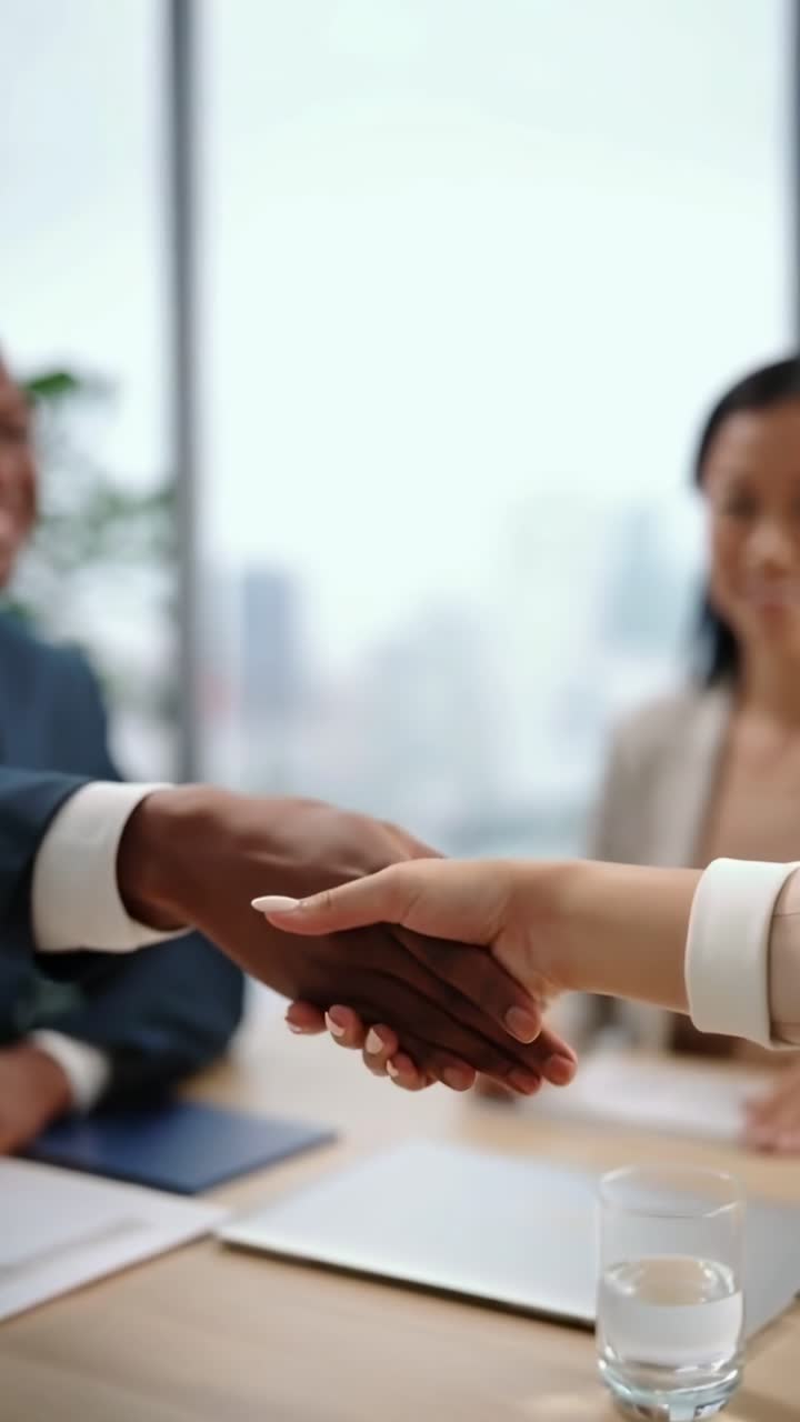 Video ravvicinato di una stretta di mano durante una riunione di lavoro, ripreso da un angolo laterale, che trasmette collaborazione