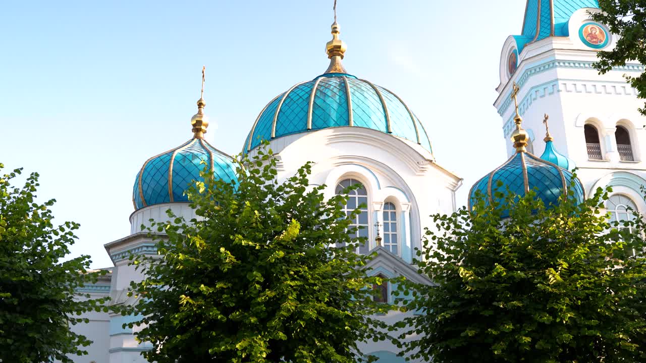 Собор Святых Симеона и Анны, православная церковь с красочными золотыми и синими куполами. Подъем камеры сквозь деревья, Елгава