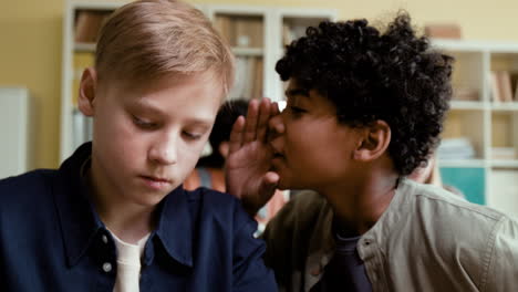 boys whispering to each other in a classroom