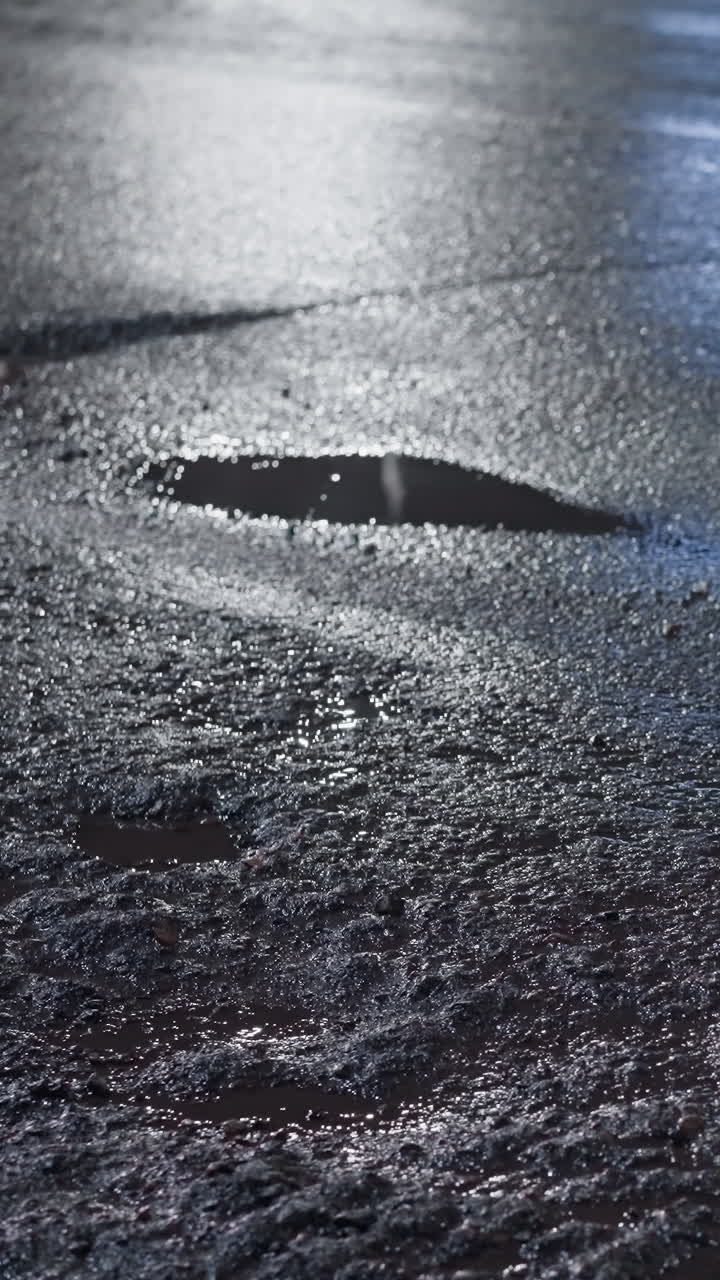 밤에 은 도로의 클로즈업 뷰, 자동차가 지나갈 때 반이는 표면에 빛의 반사를 보여줍니다.