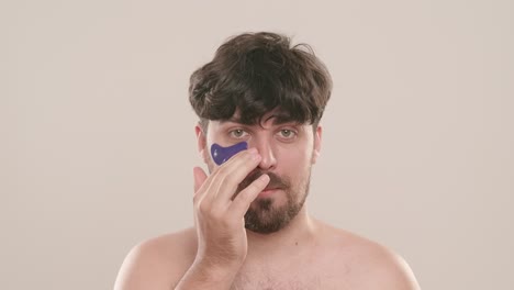 man using gua sha tool on face