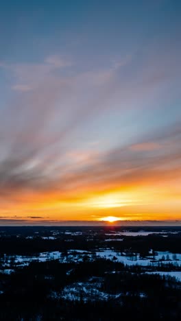 vertical winter sunset hyperlapse in countryside landscape. aerial drone view of sun setting over the horizon. vibrant sky over the nature.