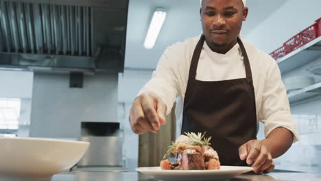 african american male chef decorating meal in kitchen, slow motion