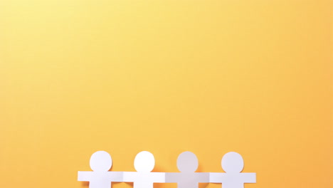primer plano de personas con las manos hechas de papel blanco sobre fondo amarillo con espacio de copia