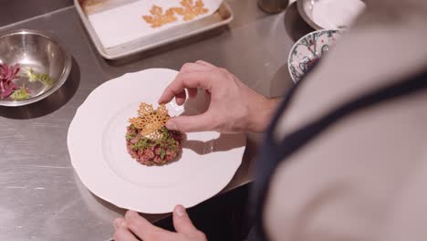 el cocinero masculino puso decoración en el plato blanco con aperitivo y pasó el plato para servir