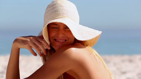mujer con un sombrero de paja y sentada en la playa