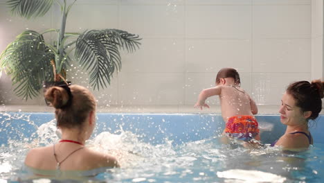 happy middle-aged mother swimming with cute adorable baby in swimming pool. smiling mom and little child, newborn girl having fun together. active family spending leisure and time in spa hotel.