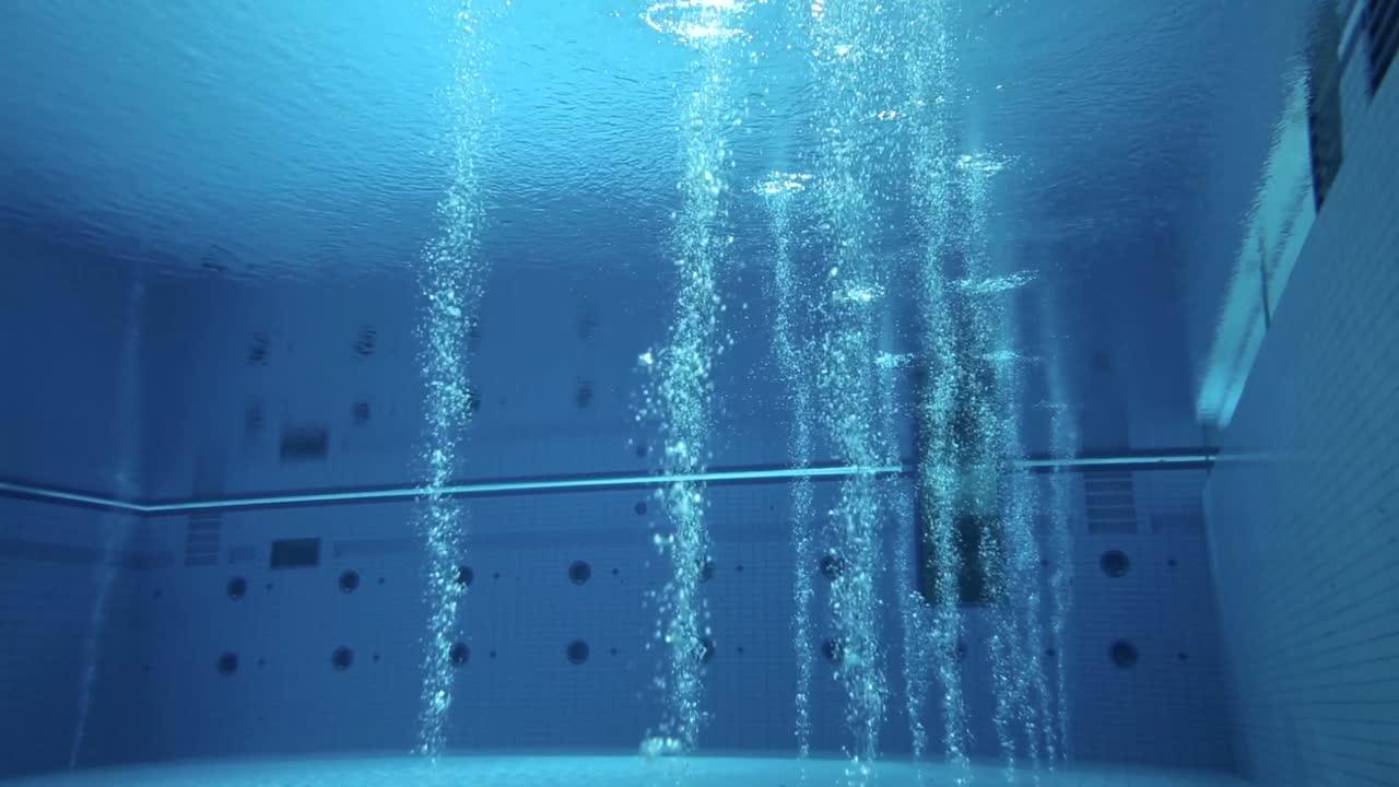 Long shot of an active, deep, Olympic-sized diving pool with bubbles