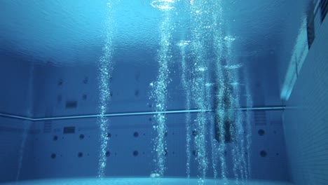 long shot of an active, deep, olympic-sized diving pool with bubbles