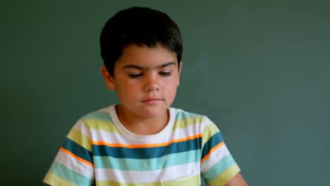 Caucasian-schoolboy-playing-with-football-against-green-board-in-classroom-4k