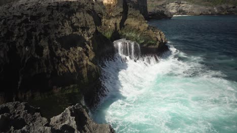 aerial view of the crystal blue water of angels billabong in nusa penida, indonesia with the waves hitting the cliffs