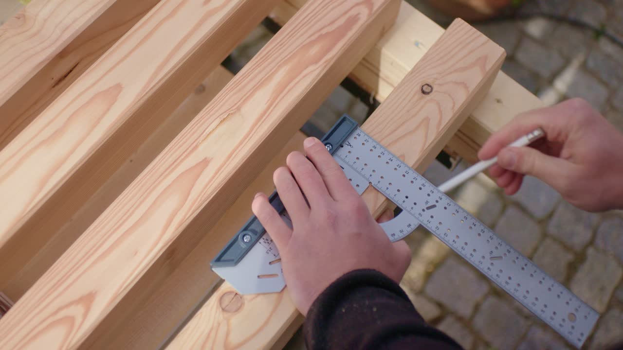 L'operaio misura il legno con il righello.