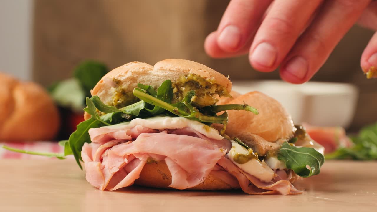 Mortadella ham sandwich, Traditional italian focaccia filled with thin pesto slices of mortadella, served by chef man in cafe restaurant. Macro of traditional italian spanish tapas antipasti.