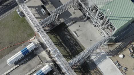 drone perspective directly above cylindrical storage tanks and interconnected piping at factory complex, industrial layout, castets, france