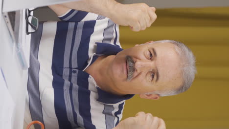 video vertical de un anciano trabajador de oficina en casa hablando motivadoramente a la cámara.