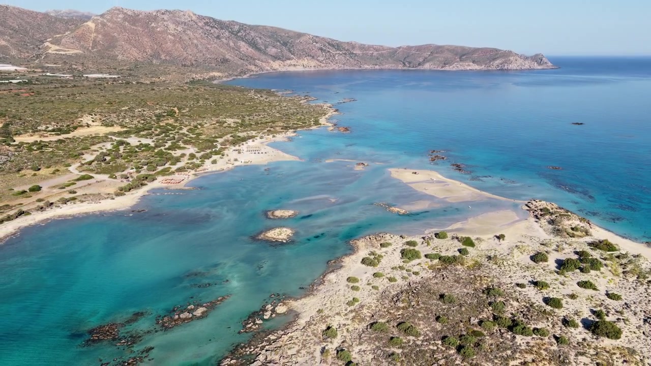 Vue aérienne par drone à haute altitude des bancs de sable et d'un lagon turquoise peu profond avec des montagnes en arrière-plan, Elafonissi, Grèce