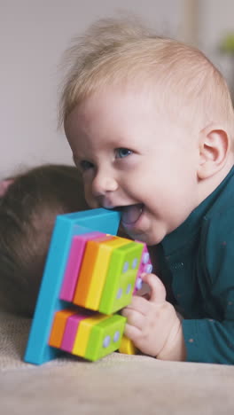 happy blonde girl hugs little brother with funny toy lying on large comfortable bed in light room at home closeup