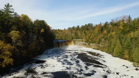 aerial, river waterfall with white frothy water in fall forest, pedestal up