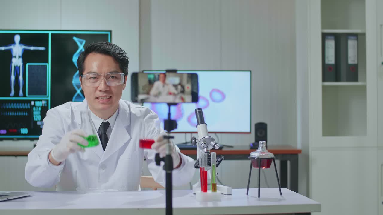 Asian Scientist Man Using Smartphone Recording Video While Researching In The Laboratory, He Holding Test Tube And Speaking