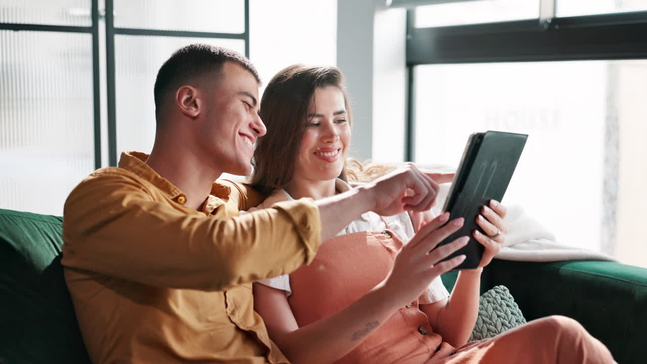 Couple laughing while looking at tablet