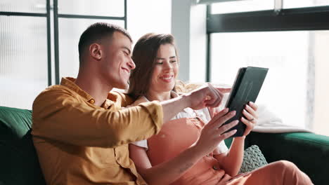 couple laughing while looking at tablet