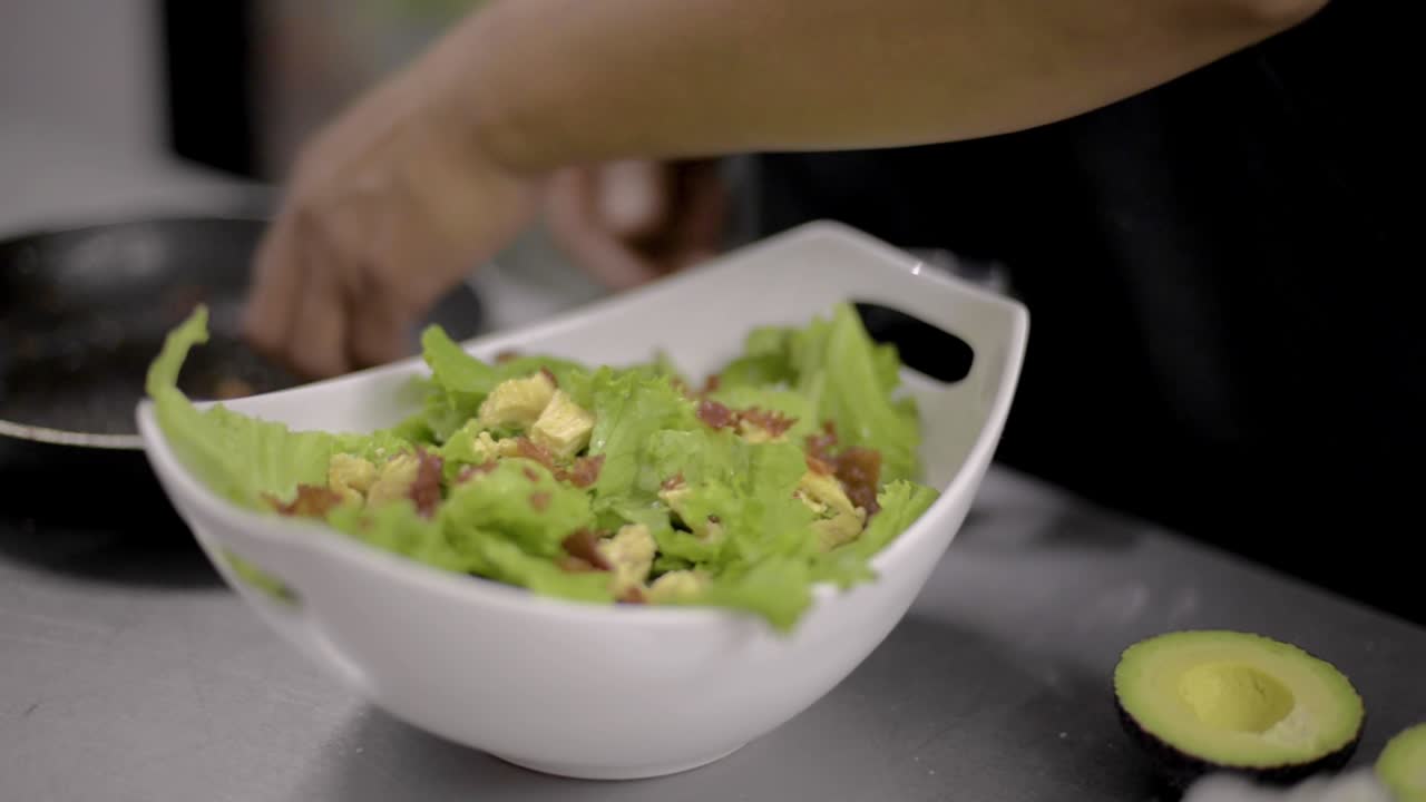 Woman chef cook preparing a salad cutting and adding a chicken breast at a local restaurant diner cafe in Mexico latin america