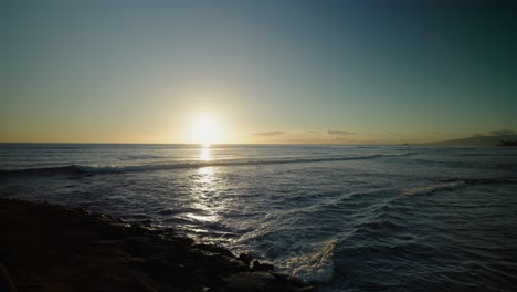 Hawaiian-sunset-with-paddle-boarder-paddling-into-frame-through-waves