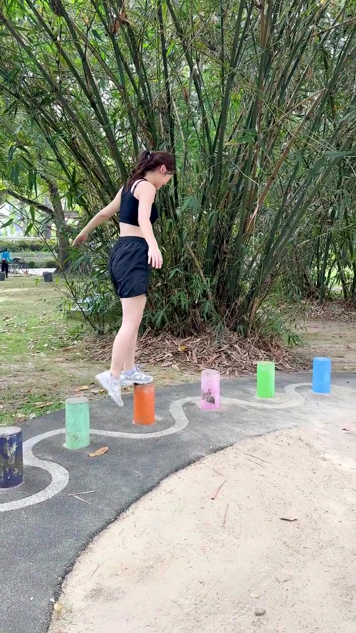 Una mujer tailandesa atlética recorre con cuidado una colorida pista de obstáculos al aire libre en el Parque Benjakitti.